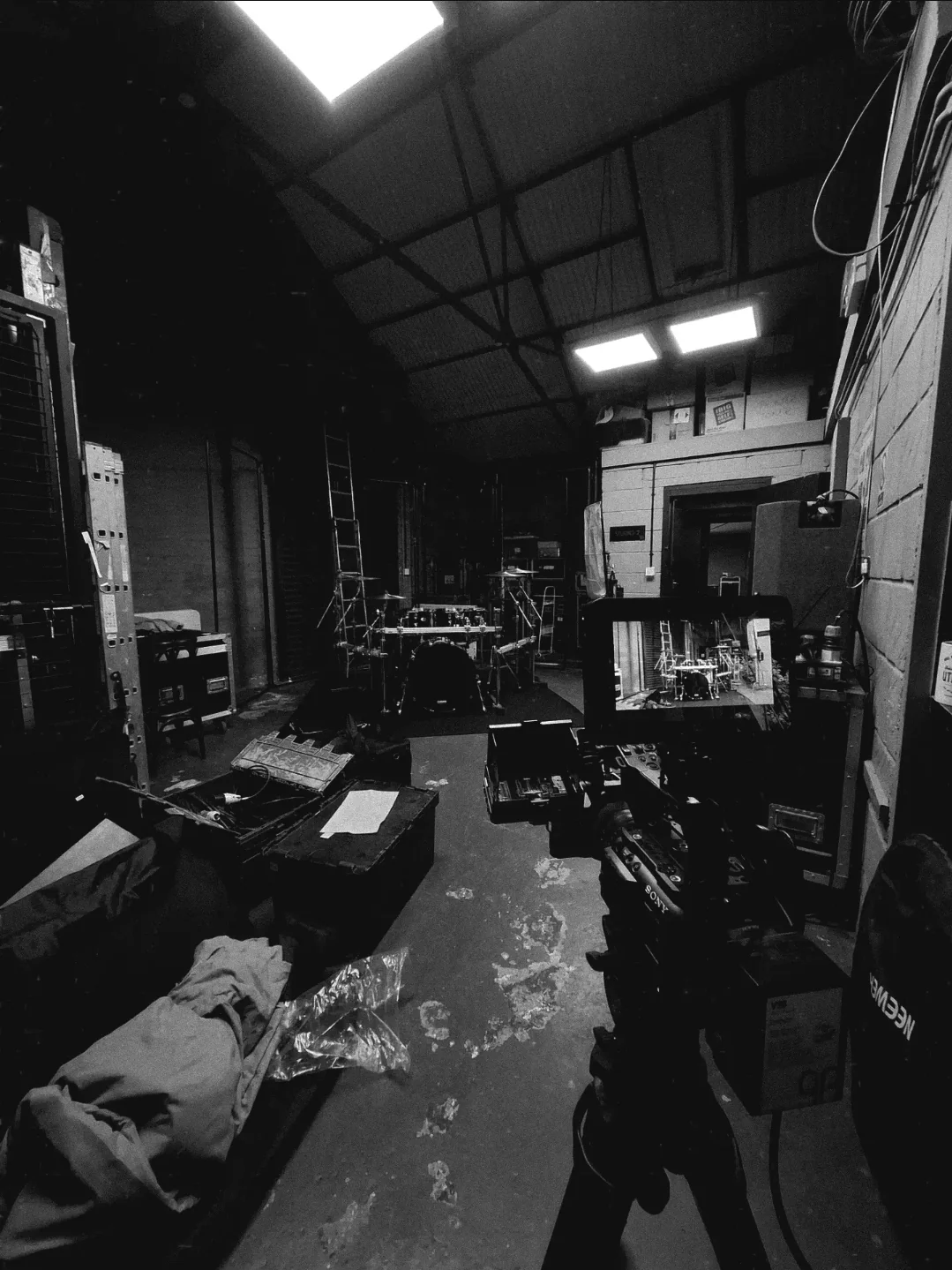 Camera rig aimed at the drum kit set up in the studio, with road cases and lighting around the set