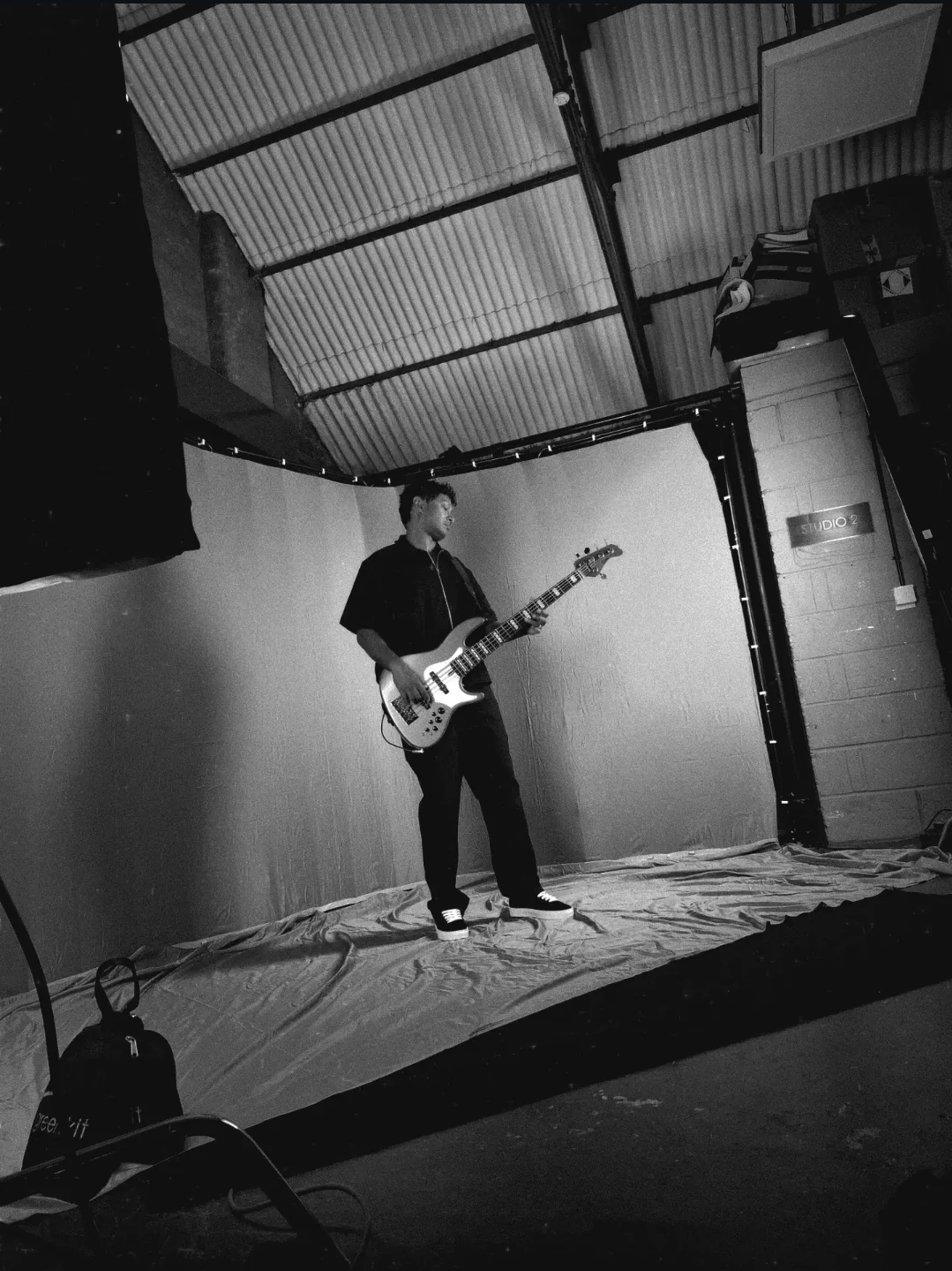 The bassist playing on the draped stage beneath the studio roof