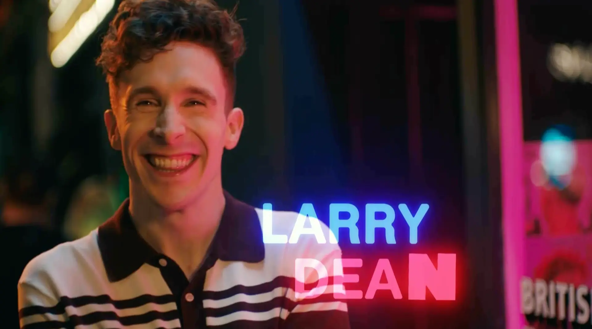 Larry Dean in the SNL UK Series 2 opening titles, with blue and pink neon name graphics