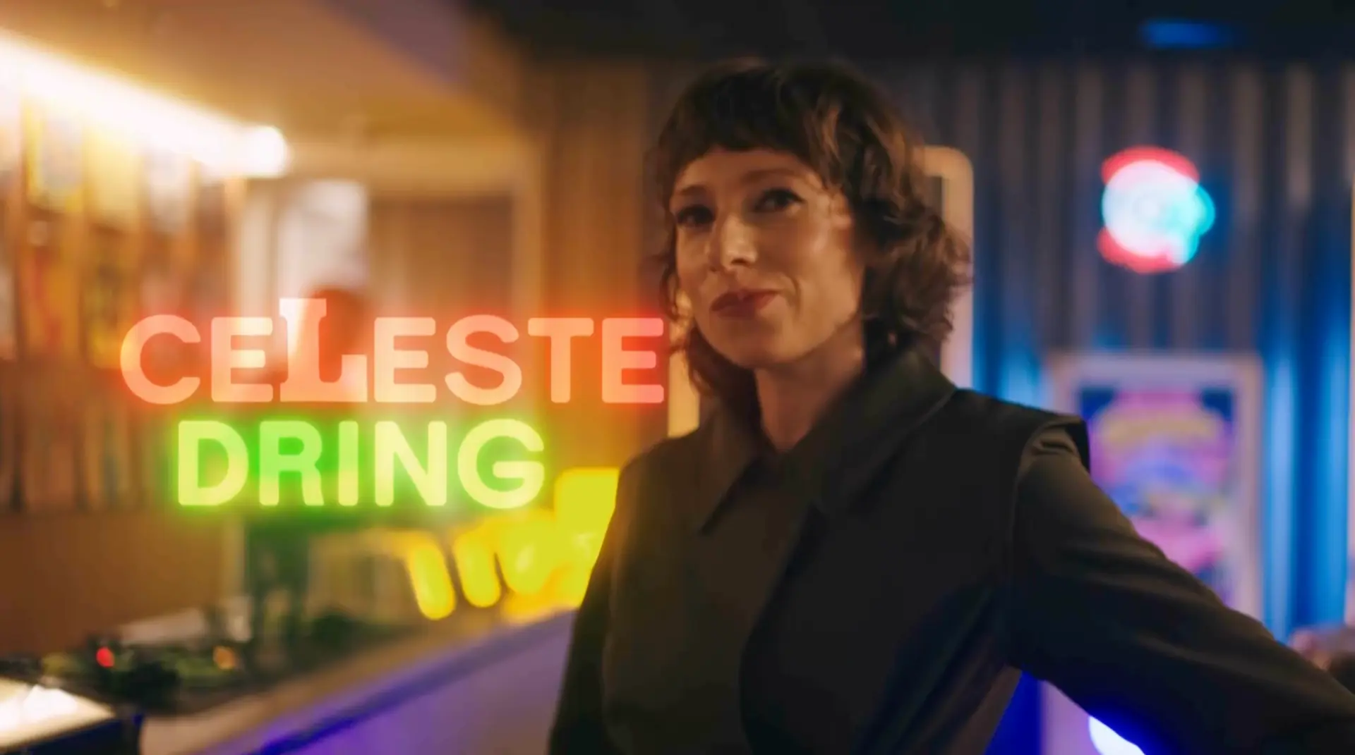 Celeste Dring in the SNL UK Series 2 opening titles, with orange and green neon name graphics